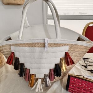 White straw and leather basket with colorful pompoms.