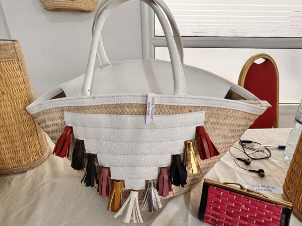 White straw and leather basket with colorful pompoms.