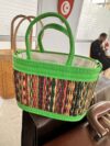 A colorful bag made from multicolored natural fibers and green leather.