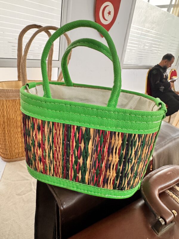 A colorful bag made from multicolored natural fibers and green leather.