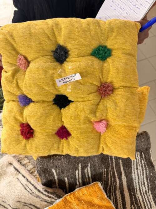 Coussin en laine jaune à pompons